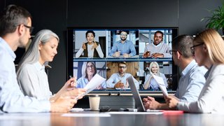 Global corporation online videoconference in meeting room with diverse people sitting in modern office and multicultural multiethnic colleagues on big screen monitor. Business technologies concept.