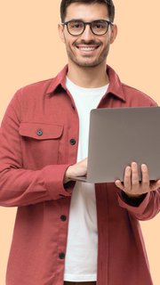 Young man standing holding laptop and looking at camera with happy smile