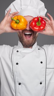 Cheerful chef with colorful peppers