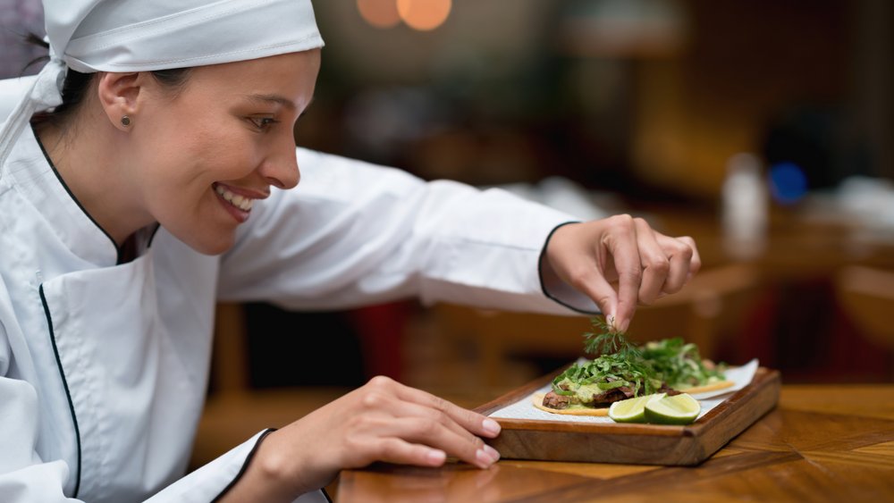 Happy cook decorating a plate at a restaurant