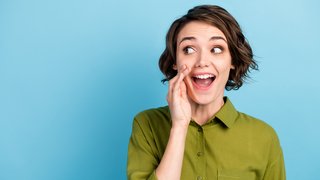 Photo portrait of young pretty girl with short hair telling secret information rumouring gossiping wearing green shirt isolated on blue color background