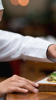 Happy cook decorating a plate at a restaurant