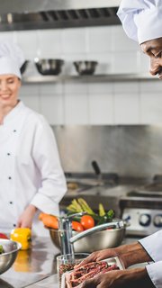 smiling african american chef holding tray with raw meat at restaurant kitchen