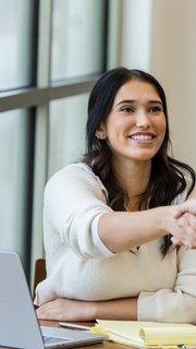 Young adult female business owner shakes hand with unrecognizable client