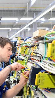 young apprentice assembles components and cables in a factory in a switch cabinet - workplace industry with future